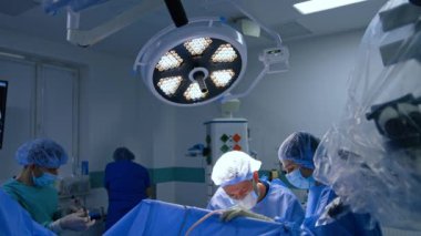 İki doktor hastanın ameliyatının üzerine eğildi. Sinir cerrahı için makas kullanan erkek asistan..