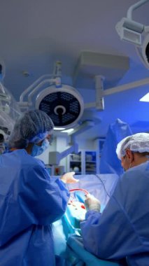 Erkek cerrah, içi kan dolu bir cihaz kullanıyor. Doktora değişiklik olsun diye başka bir enstrüman verildi. Dikey video.