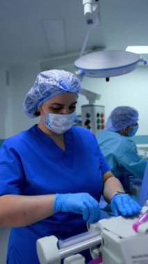 Ameliyathanede çalışan kadın hemşire ekipmanları ayarlıyor. Sıhhiyeci infüzyon pompasını ilaçla doldurur. Dikey video.