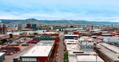 Modern bir şehrin sanayi bölgesindeki düşük katlı büyük binalara iniyor. Fremont Köprüsü Portland, Oregon 'daki Willamette Nehri üzerinde..