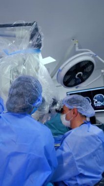 Profesyonel doktor ekibi tarafından yapılan nörocerrahi operasyon. Beyin cerrahları mikroskop kullanırlar. Dikey video.