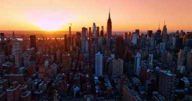 New York manzarasının üzerinde güneş batıyor. İnanılmaz gökdelenler yumuşak turuncu ışıkla aydınlatılıyor. Hava perspektifi.