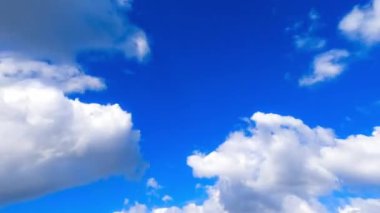 Yumuşak tüylü beyaz bulutlar atmosferde uçuşuyor. Mavi gökyüzünü kaplayan bulutların alçak açılı görüntüsü. Zaman Uygulaması.