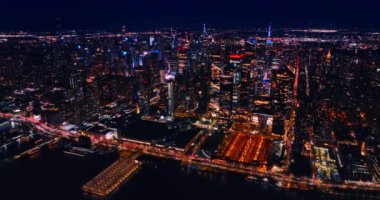 New York 'u havadan aydınlatmış. İnsansız hava aracı gece vakti göz kamaştırıcı şehir panoramasında uçuyor..