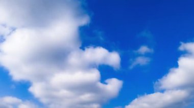 Mavi gökyüzünde beyaz pamuk bulutları. Rüzgâr ufukta bulutları savuruyor. Düşük açı. Zaman Uygulaması.