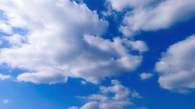 Yumuşak pamuk bulutları gökyüzünde dönüşüyor. Güneş atmosferdeki beyaz bulutları aydınlatıyor. Düşük açılı bakış açısı. Zaman Uygulaması.