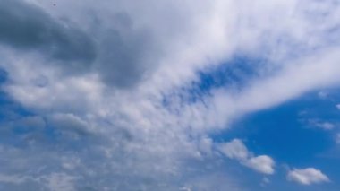 Atmosferde süzülen beyaz ve gri bulutlar. Mavi gökyüzünde alçak açılı bir bakış açısıyla değişen bulutlar. Zaman Uygulaması.