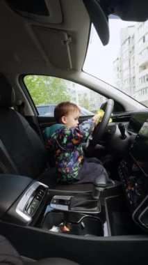 Babasının küçük yardımcısı arabada oturuyor. Bab Boy arabadaki panelleri temizlemek için sarı bez kullanıyor. Dikey video.