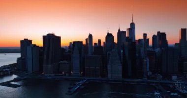 Doğu Nehri 'nin kıyısındaki New York' un koyu gri gökdelenleri. Pembe ve turuncu gökyüzünün altında Metropolis manzarası. Üst görünüm.