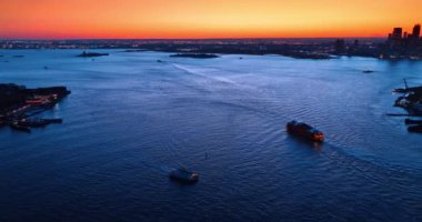 Muhteşem New York 'un su manzarasında yatlar. Turuncu gökyüzünün altındaki çarpıcı metropolde alacakaranlık. Hava perspektifi.