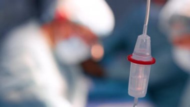 Çözüm su deposunun içine damlıyor. Kapatın. Arka planda bulanık doktor siluetleri.