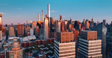 Manhattan mimarisi batan güneşin turuncu sıcak ışığında. Gün batımında tepeden New York manzarası.