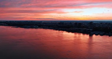 Pembe gökyüzü ve bulutlar Doğu Nehri 'nin su yüzeyine yansıyor. Hava perspektifinden New York 'un karanlık manzarası.