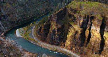 Güzel uçurumlar dar nehrin üzerinde kayaların arasında kıvrılıyor. İnsansız hava aracı görüntüleri dağların üzerinde, ayakları üzerinde otoban var..