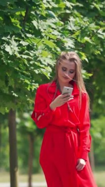 Şehirde akıllı telefon kullanan bir kadın. Şehir merkezinde akıllı telefonu olan genç bir kadın. Dikey video