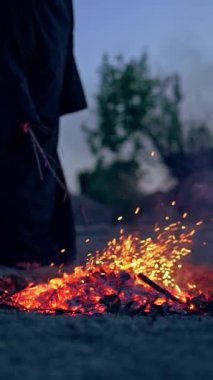 Şenlik ateşinin yanındaki siyahlı cadı. Şenlik ateşinin etrafında dolaşan mistik cadı. Dikey video