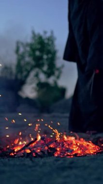Şenlik ateşinin yanındaki siyahlı cadı. Şenlik ateşinin etrafında dolaşan mistik cadı. Dikey video