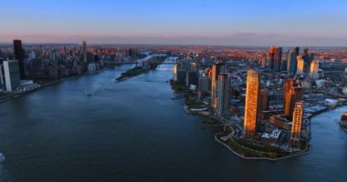 Gün batımında New York 'ta su üzerinde uçmak. Bazı binaların yüzleri batan güneşin turuncu ışığıyla aydınlanır..
