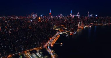 Karanlık Doğu Nehri 'nin rıhtımındaki iyi aydınlatılmış otobanın yanından bir sürü araba geçiyor. Güzel New York geceleri ışıkları açıyor. Hava görünümü.