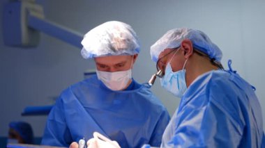 Modern ameliyathanede işbirliği yapan iki doktor. Cerrahlar işlem sırasında iletişim kurarlar.