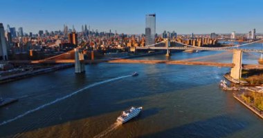 New York 'taki East River' ın yanındaki Brooklyn Köprüsü 'nün altında tekne yüzüyor. Metropolis mimarisi parlak güneş tarafından aydınlatılır. Üst görünüm.