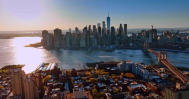 Günbatımında Brooklyn üzerinde East River rıhtımına yakın bir uçuş. Arkaplanda Manhattan gökdelenlerinin silüeti.