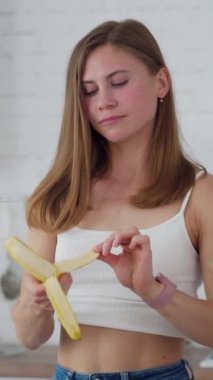 Mutfakta genç bir kadın var. Sağlıklı yemek yiyen genç bir kadının portresi. Dikey video