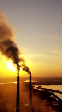 Gün batımına karşı tüttürme boruları. Ağır dumanlı sanayi bacaları hava kirliliğine neden oluyor. Dikey video