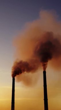 Dumanlı pipo ekin. Elektrik santralinden gelen gri dumanlı yüksek baca borularının hava görüntüsü. Dikey video