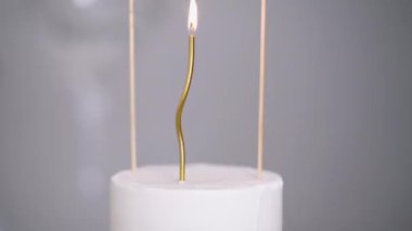 Beyaz pastada yanan kıvrımlı altın mum. Yukarıda 