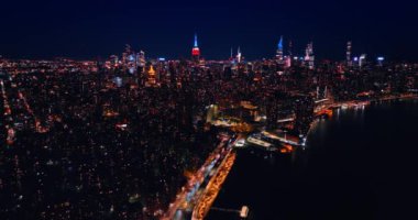 New York 'ta ışıklarla kaplı karanlık binaların siluetleri. Metropolis ve Doğu Nehri 'nin gece görüş açısı.