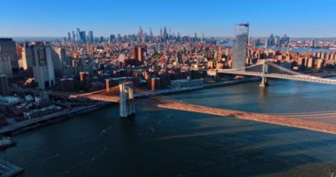 Brooklyn ve Manhattan Köprüleri batan güneşin altında. Arka planda New York 'un güneşli manzarası. Üst görünüm.