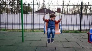 Çocuk parkında sallanan beyaz bir çocuk var. Bebeğim sonbaharda dışarıda eğleniyor..