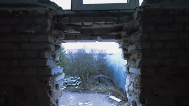 Kışın açık havada, tuğla duvardaki delikten bak. İnşaat malzemeleri ve sökülmüş iskeleleri olan büyük bir oda..