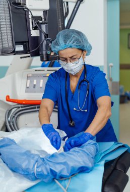 Klinik bir ortamda tıbbi profesyonel hazırlık ekipmanları. Mavi önlüklü bir sağlık görevlisi hastanede güvenli bir ortam sağlarken tıbbi araçlar düzenler..