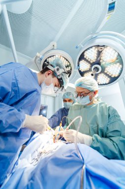 Cerrahlar modern hastane ortamında karmaşık bir ameliyat gerçekleştiriyorlar. İyi donanımlı bir ameliyathanede cerrahi bir prosedüre odaklanan bir cerrah ekibi.