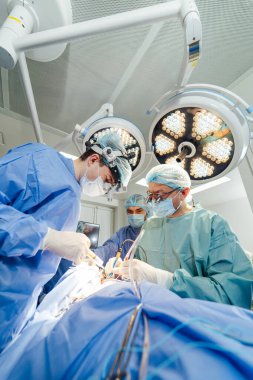 Yüksek teknolojili bir ameliyathanede cerrahi ekip çalışıyor. Yetenekli bir cerrahi ekibi kritik bir sağlık operasyonu sırasında iyi donanımlı bir ameliyathanede bir prosedüre odaklanır..