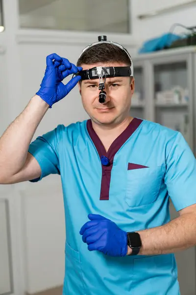 Stock image Healthcare pro prepping for clinical exam. A healthcare professional adjusts his headlamp before examining a patient in a clinical environment