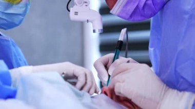 Cerrahın eldivenli elleri elektrocerrahi aletleri ve metal forsepsleri tutar. Endokrin oftalmopati prosedürünü kapatın..