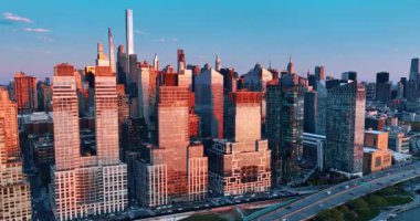 Yüksek binaların ayna pencereleri gün batımında pembe ışığı yansıtıyor. İHA görüntüleri New York 'un mimarisine doğu nehrinin kıyısından yaklaşıyor..