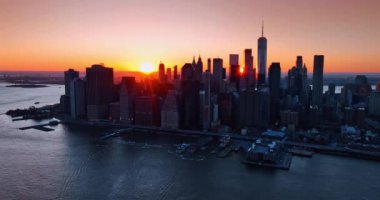 New York 'un karanlık silueti altın saatinde. Parlak turuncu güneş arka planda gökyüzünü pembeye aydınlatıyor. Üst görünüm.