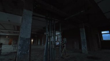 Büyük odanın içinde birkaç metal boru var. Binanın içi inşa ediliyor. Arka planda iki inşaatçı.