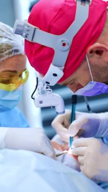 Farlı bir erkek cerrah ameliyat aletini dikkatli bir şekilde göz üzerinde kullanır. Kadın hemşirenin yardımıyla hipotiroidizmi tedavi eden bir doktor. Dikey video.