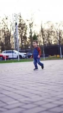 Güzel beyaz çocuk dışarı koşuyor. Küçük bebek sabun köpüklerini yakalıyor. Dikey video.