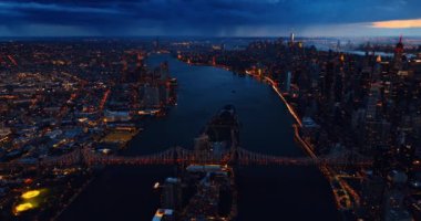 Queensboro Köprüsü gece üst perspektiften görünüyor. Arkaplanda fırtınalı bulutlu manzaralı güzel New York manzarası.