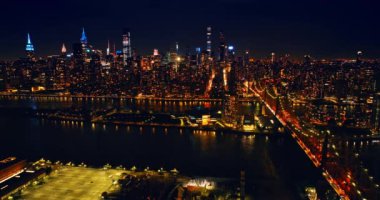 Parlak ışıklar New York, ABD 'nin panoramasını dolduruyor. Geceleri Queensboro Köprüsü 'nden bir sürü araba geçiyor. Gökdelenlerin tepeleri neon ışıklarıyla parlıyor. Üst görünüm.