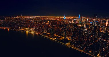 New York, ABD 'nin muazzam aydınlık manzarası. İnsansız hava aracı Doğu Nehri 'nin üzerinde yoğun trafik varken kıyıya yaklaşıyor..