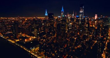 Pencerelerinde yüzlerce ışık olan kudretli New York gökdelenleri. En yüksek binaların tepeleri neon ışıklarıyla parıldıyor. Gece Metropolis 'in hava manzarası.