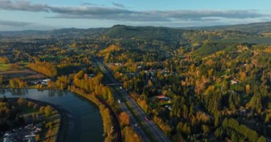 Gün batımında Oregon kırsalının yeşil dağlık manzaraları. Paralel iki otoyolun üzerindeki görüntüler ve bazı araçlar. Üst görünüm.