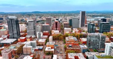 Portland, Oregon, ABD şehir manzarasının üzerinde uçuyor. Arkasında dağlar olan engin şehir manzarası.